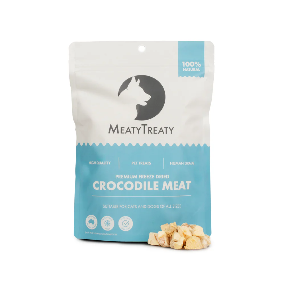 A blue and white packet of Dog or Cat treats by Meaty Treaty containing Crocodile with an example of white diced crocodile meat